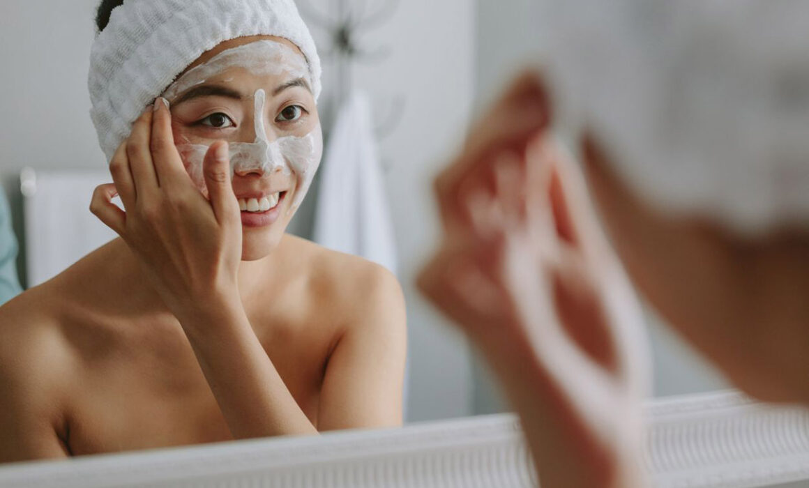 Woman in mirror applying skincare. Clean beauty product journey from lab to vanity
